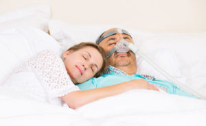 Mężczyzna śpiący w aparacie CPAP z kobietą u boku