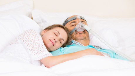 Mężczyzna śpiący w aparacie CPAP z kobietą u boku