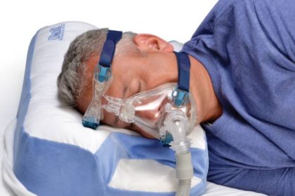 Dobór aparatu CPAP to również dobór akcesoriów. Mężczyzna śpi na poduszce do CPAP